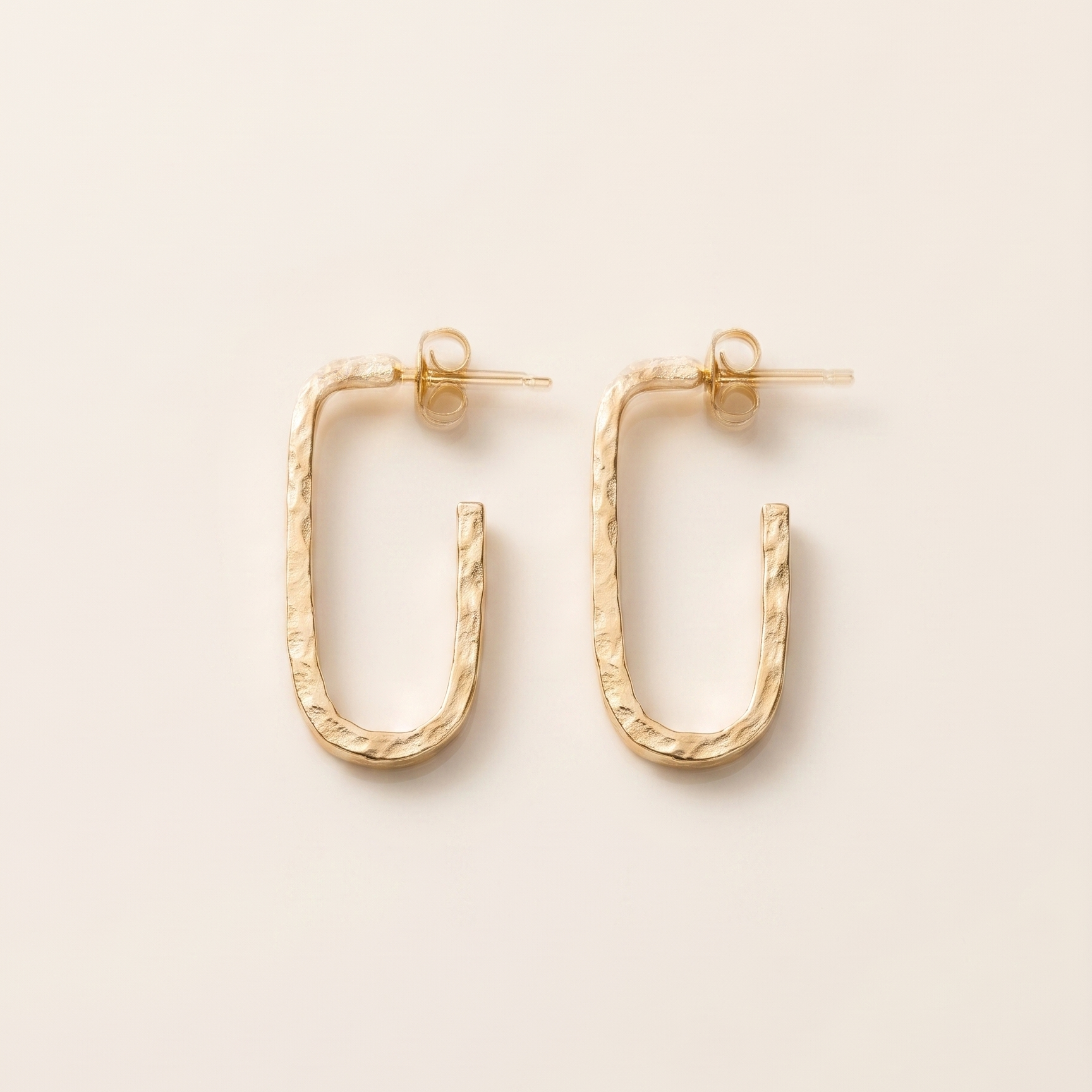 Gold hoop earrings on a beige background