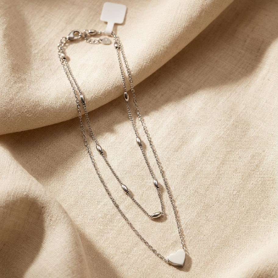 Silver bracelet with heart-shaped charm on a beige fabric background
