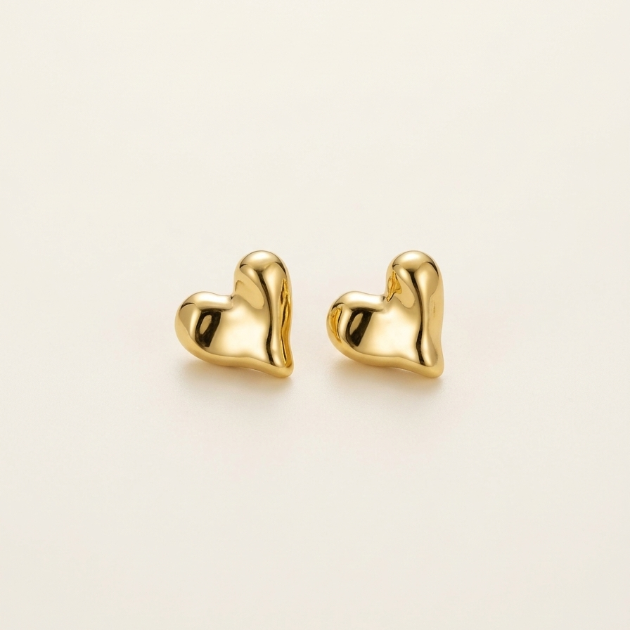 Gold heart-shaped earrings on a light beige background