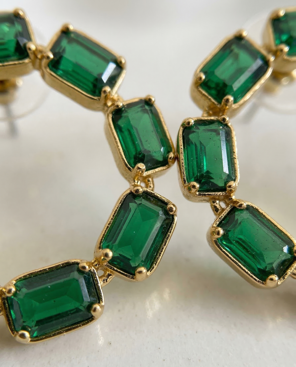 Gold and emerald green gemstone necklace on a light background