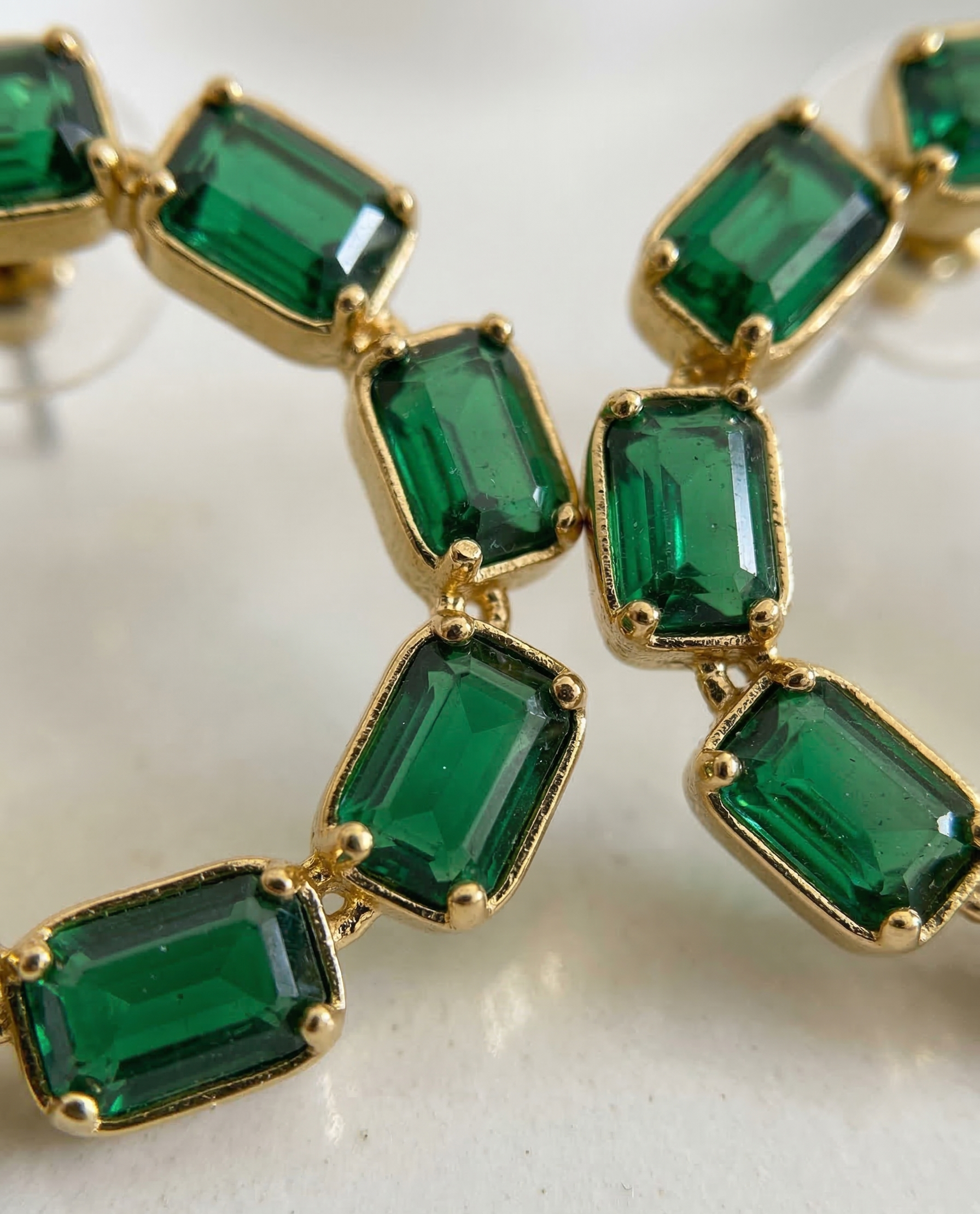 Gold and emerald green gemstone necklace on a light background