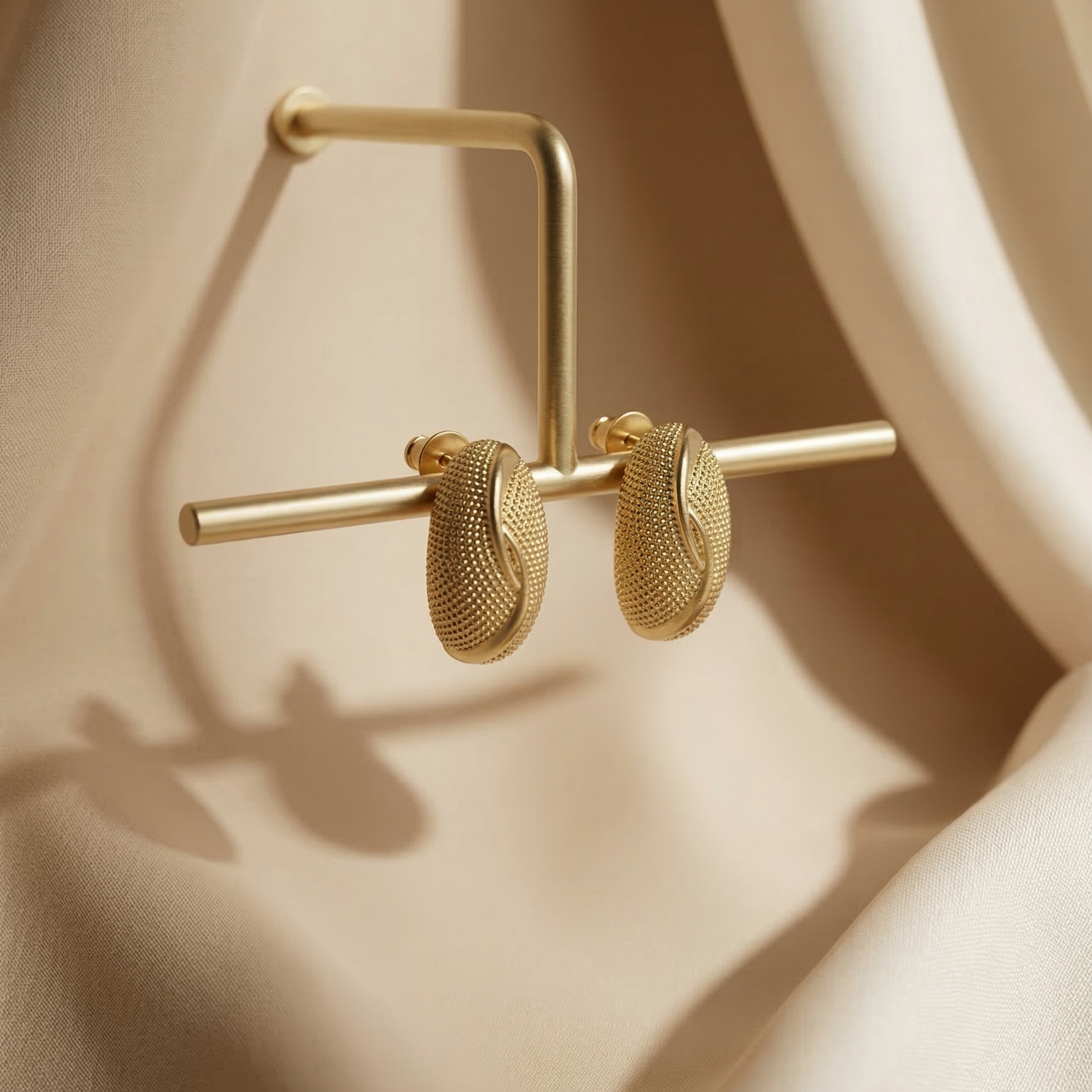 Gold hoop earrings on a beige fabric background