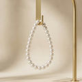 Pearl necklace on a gold stand against a beige background