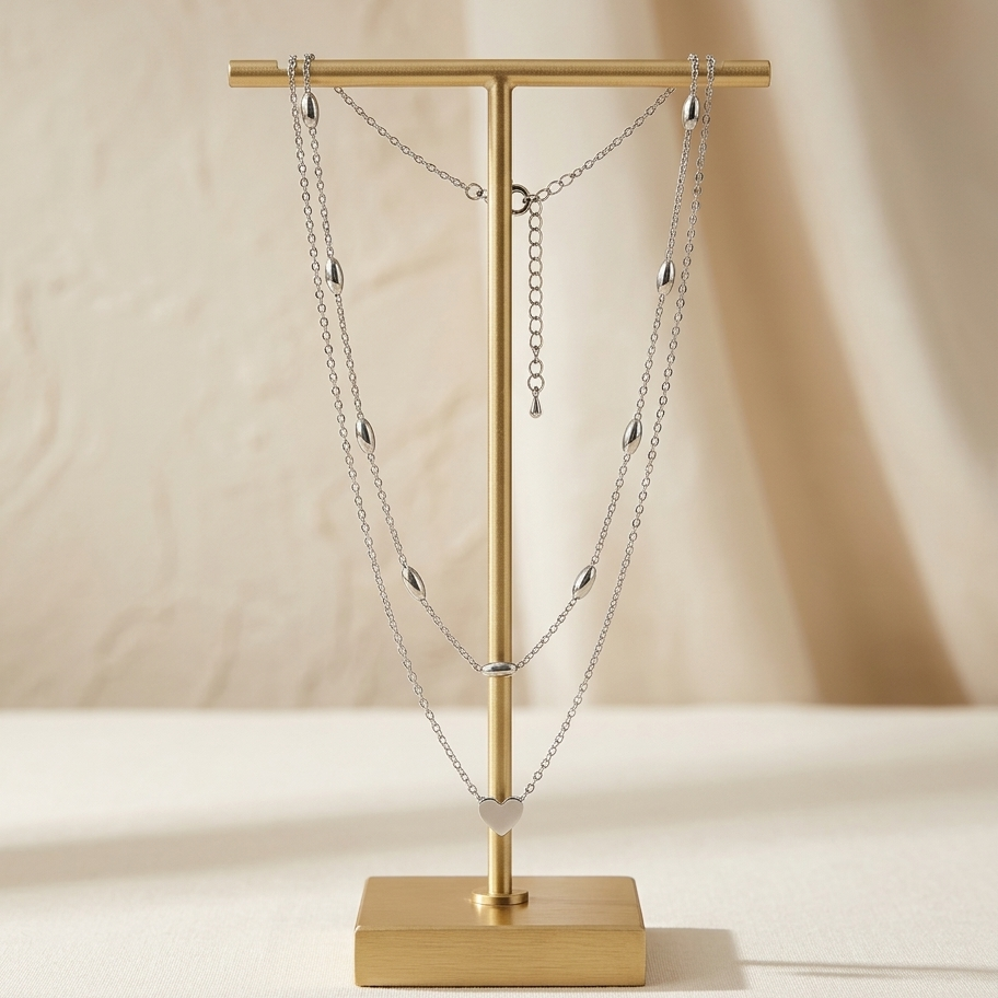 Gold necklace stand with a silver necklace on a beige background