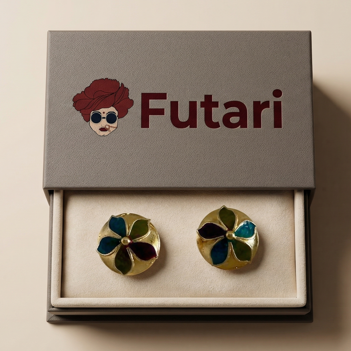 Pair of earrings in a 'Futari' branded box on a beige background