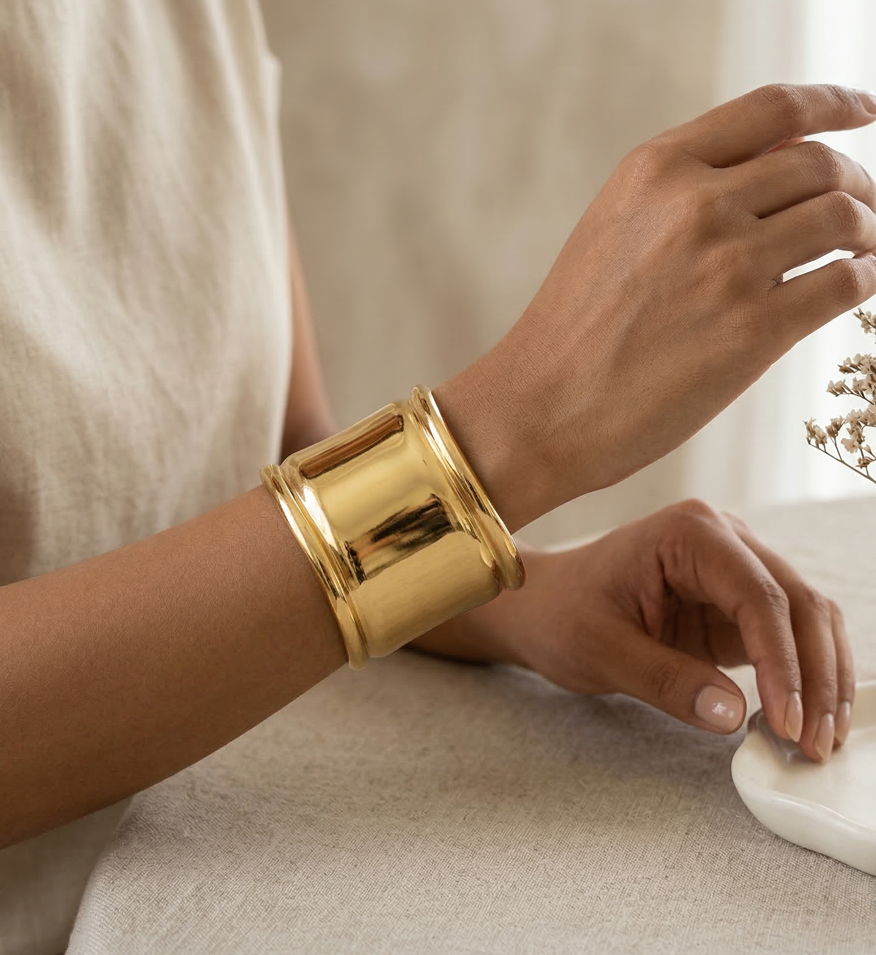 Gold bracelet on a wrist with a neutral background
