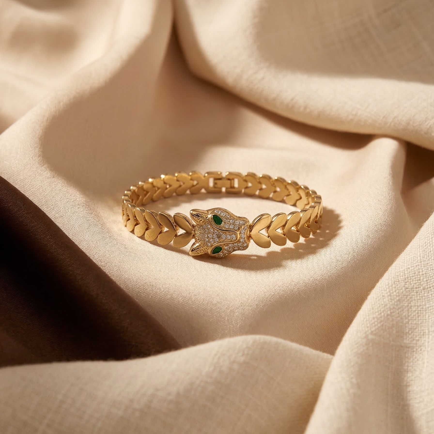 Gold bracelet with green gemstones on beige fabric