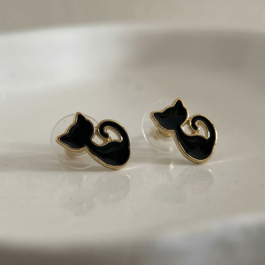 Black cat-shaped earrings on a reflective surface
