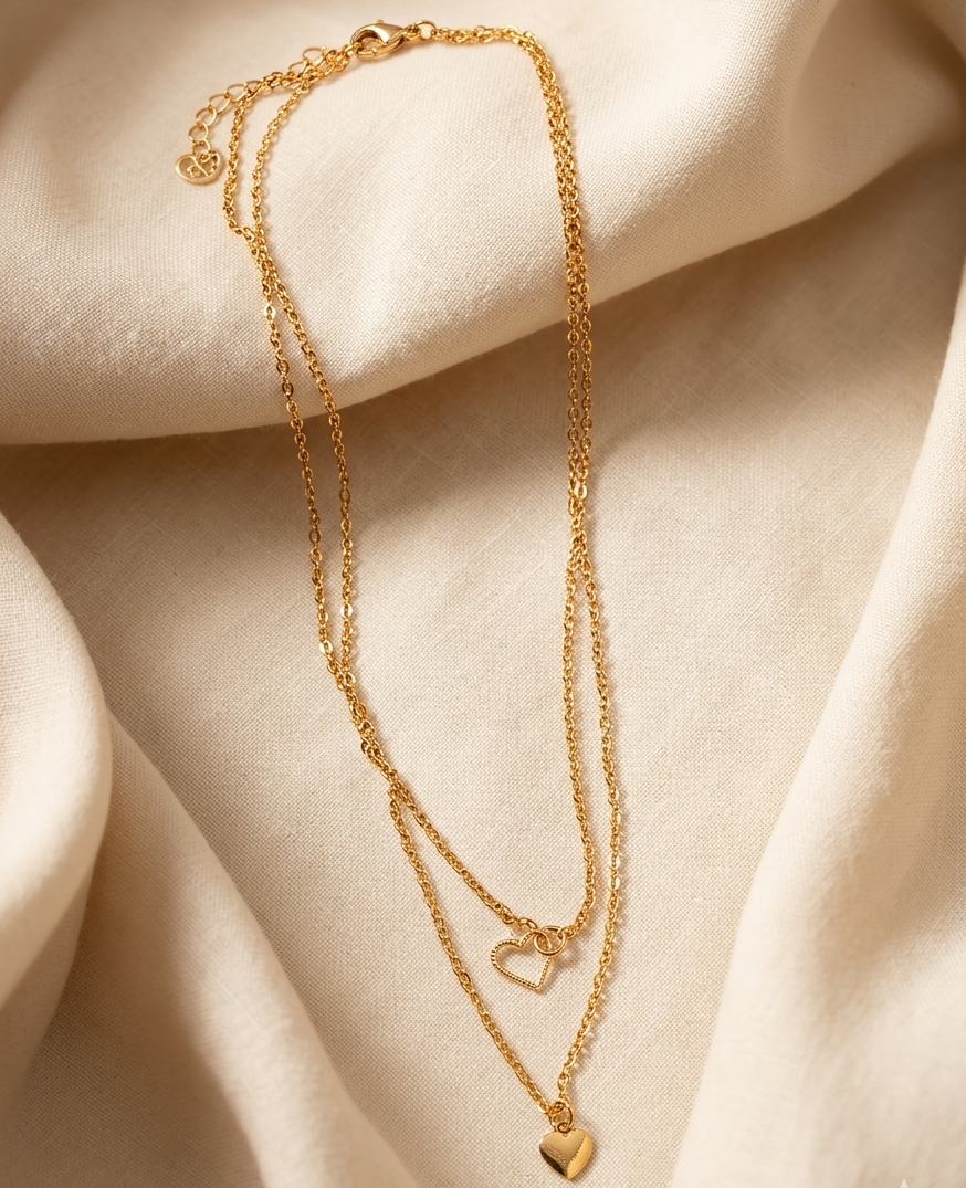 Gold necklace with heart pendants on a beige fabric background
