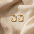Gold hoop earrings on a beige fabric background