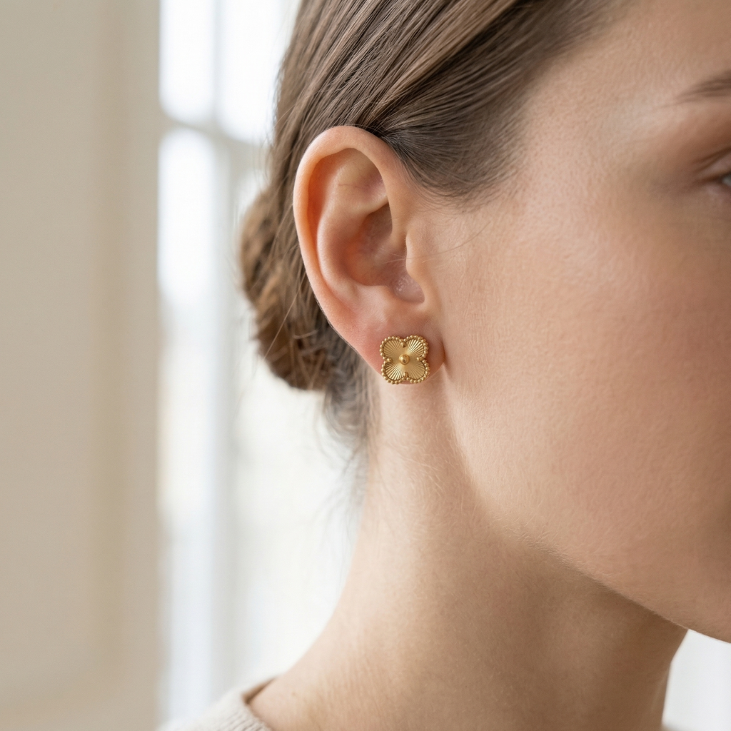 Close-up of a person wearing gold earrings with a neutral background