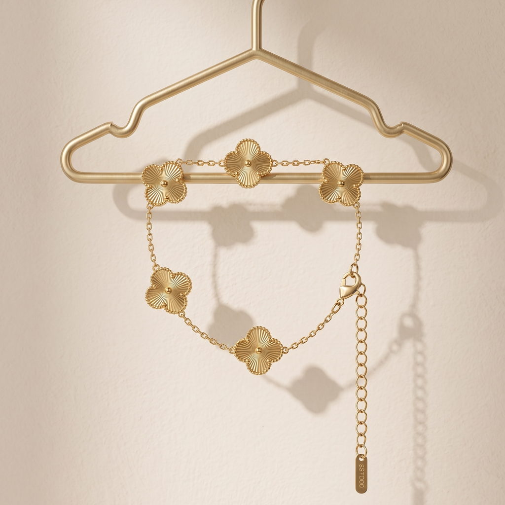 Gold necklace with floral designs on a gold hanger against a beige background