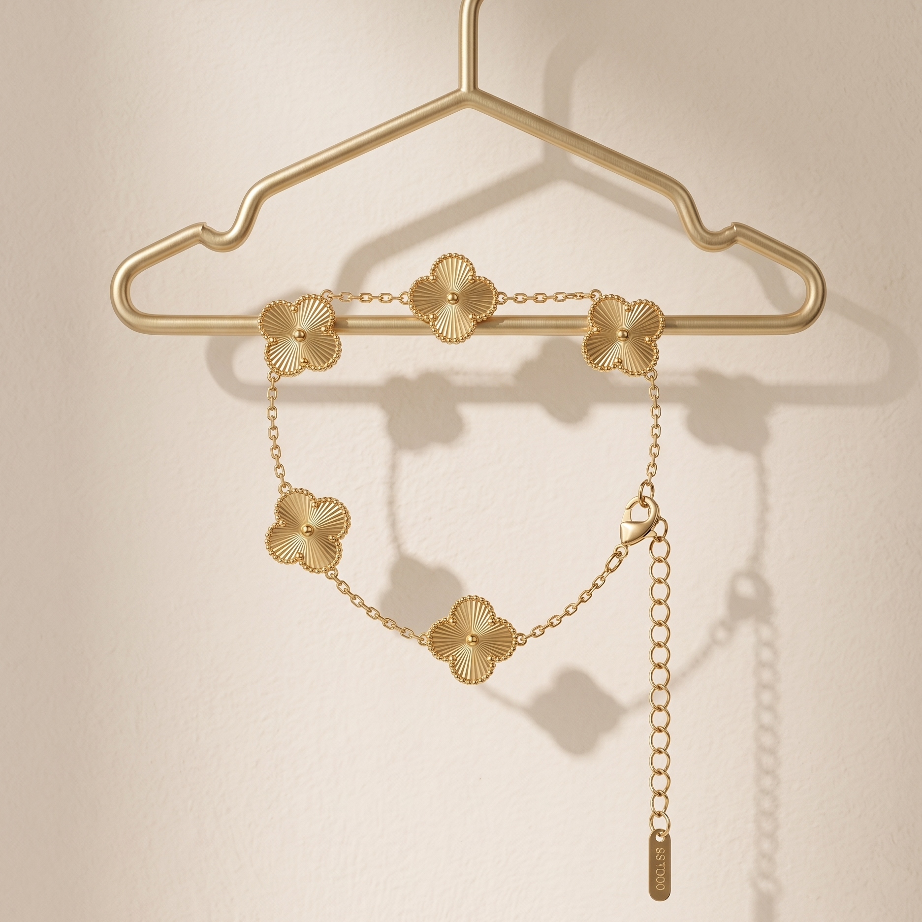 Gold necklace with floral designs on a gold hanger against a beige background