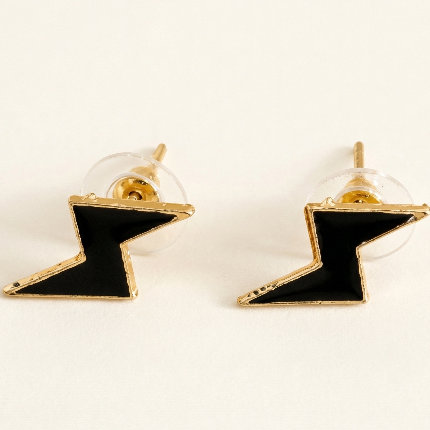 Pair of black and gold lightning bolt earrings on a white background