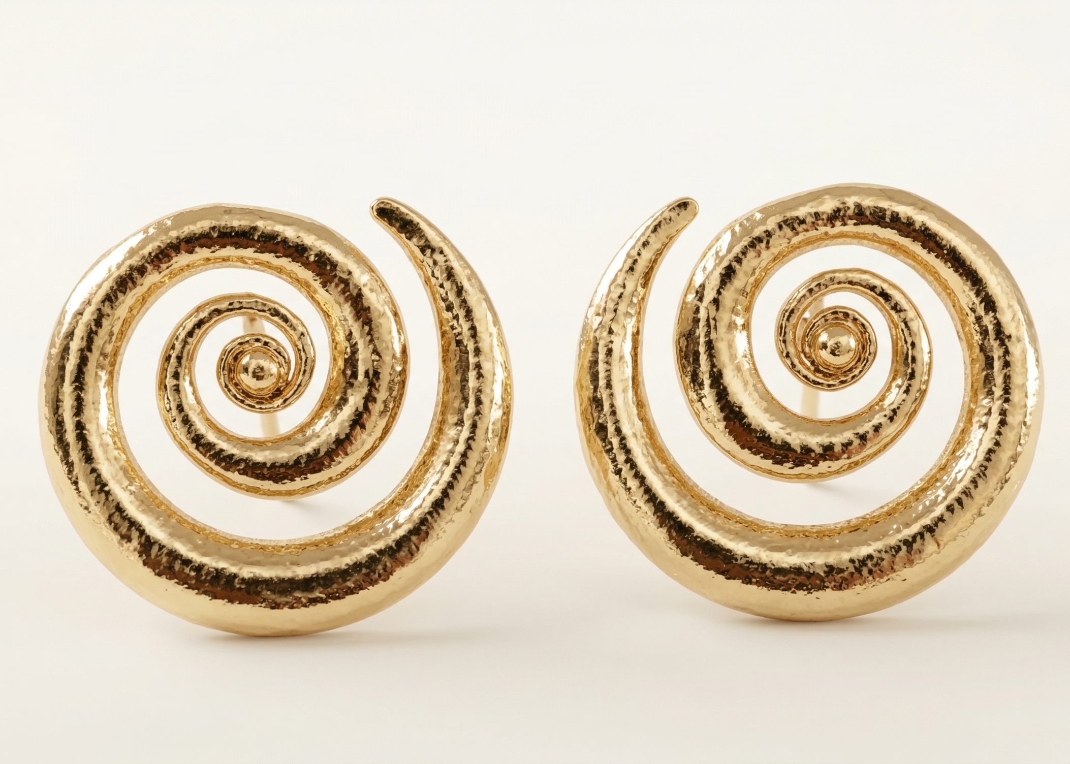 Pair of gold spiral earrings on a white background