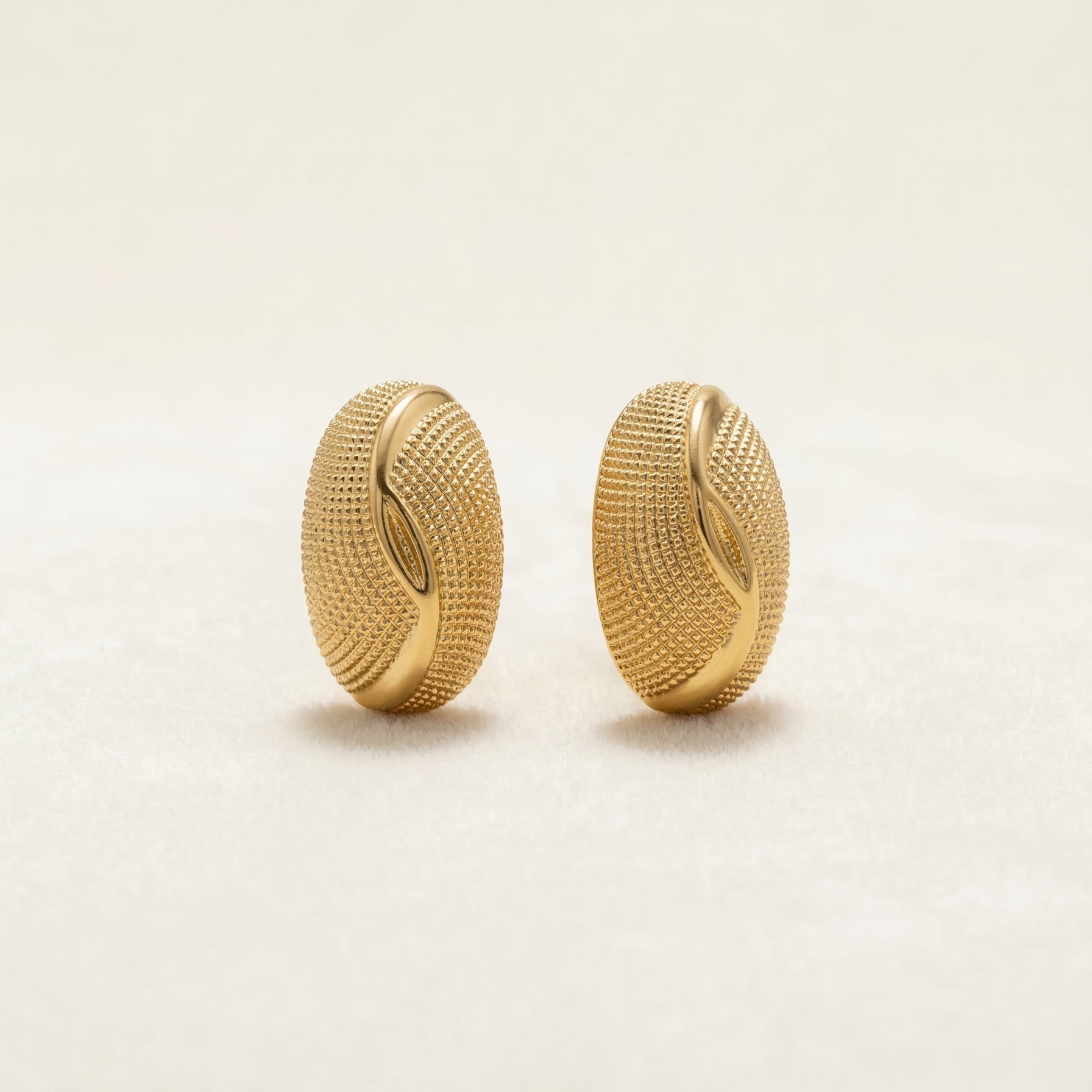 Pair of gold earrings on a light beige background