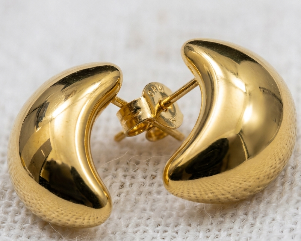 Gold hoop earrings on a textured white background
