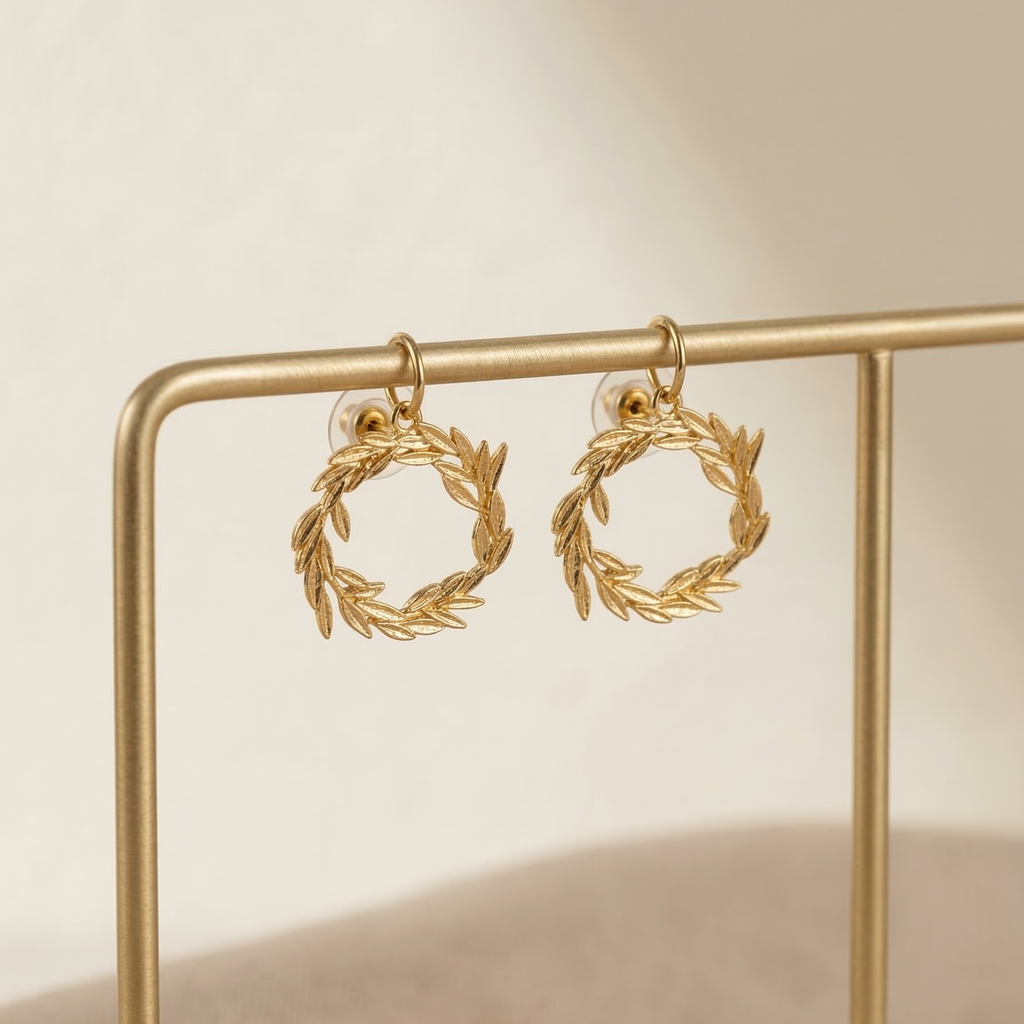 Gold wreath earrings on a gold stand against a beige background