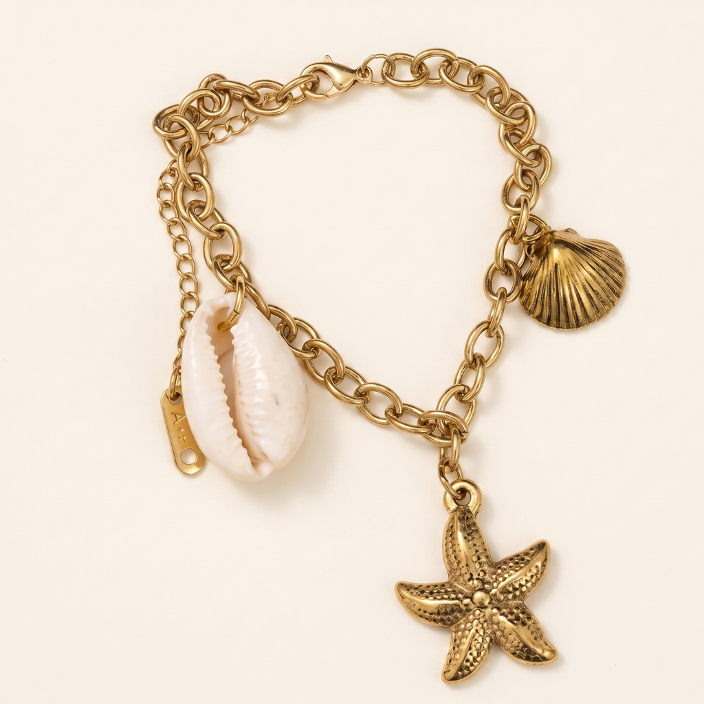 Gold chain bracelet with shell and starfish charms on a light beige background