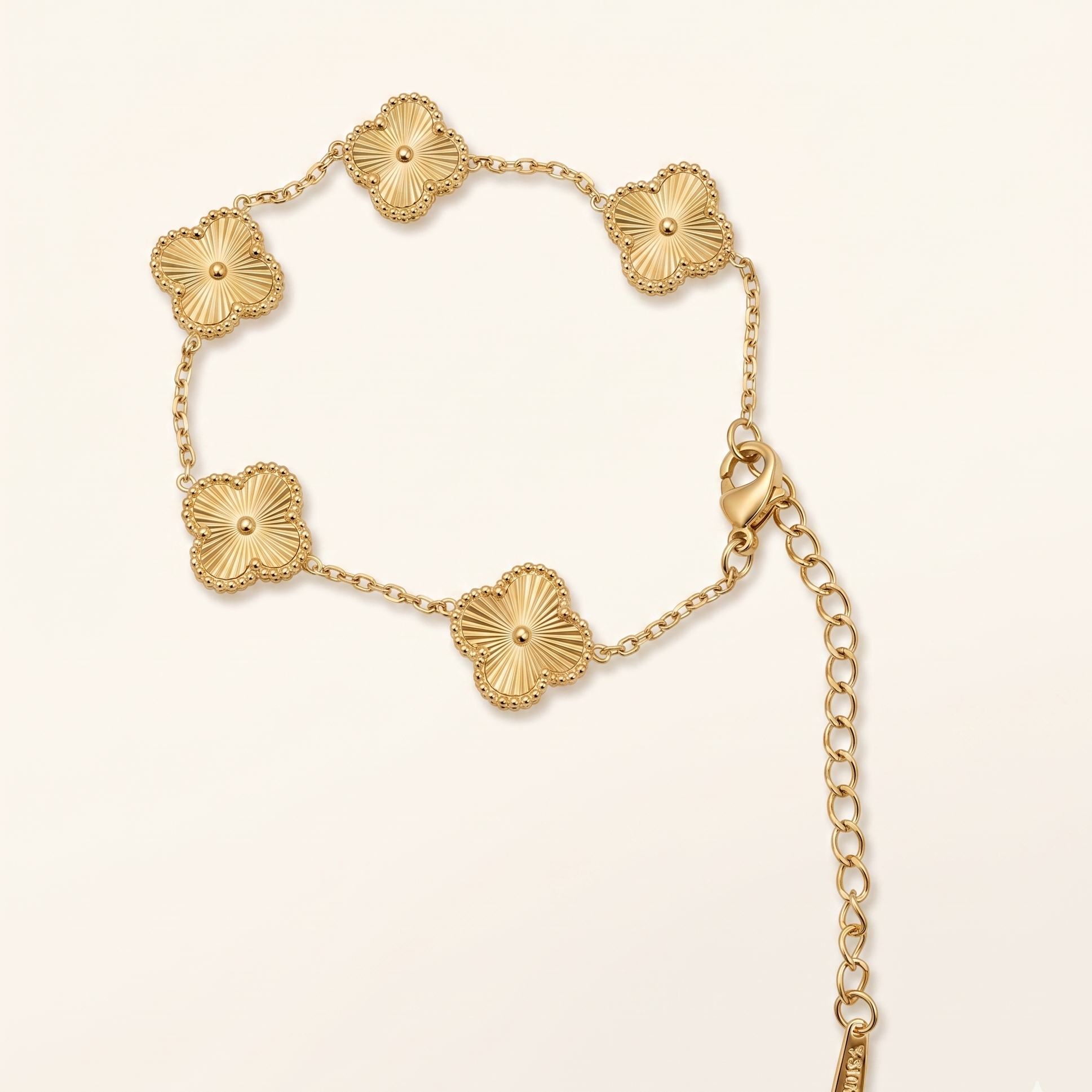 Gold bracelet with floral designs on a light beige background
