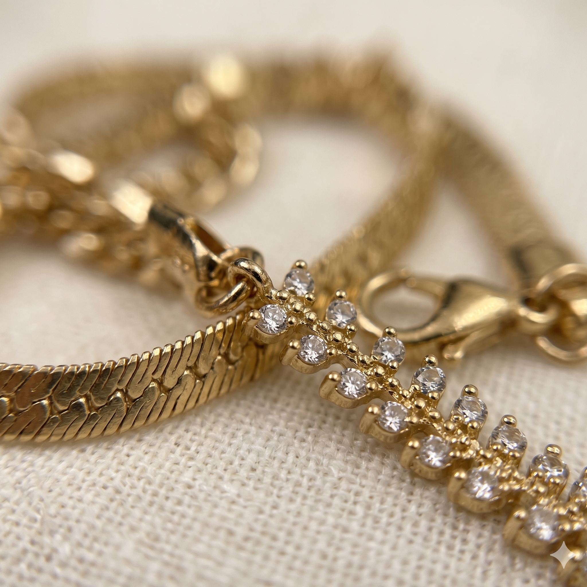 Gold bracelet with diamond charm on a beige fabric background