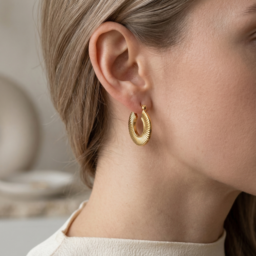 Gold hoop earring worn by a person with a neutral background