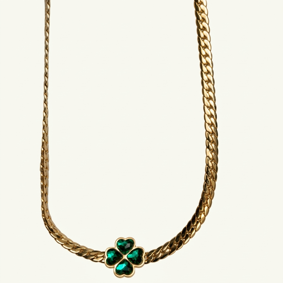 Gold necklace with a clover-shaped green gemstone on a white background