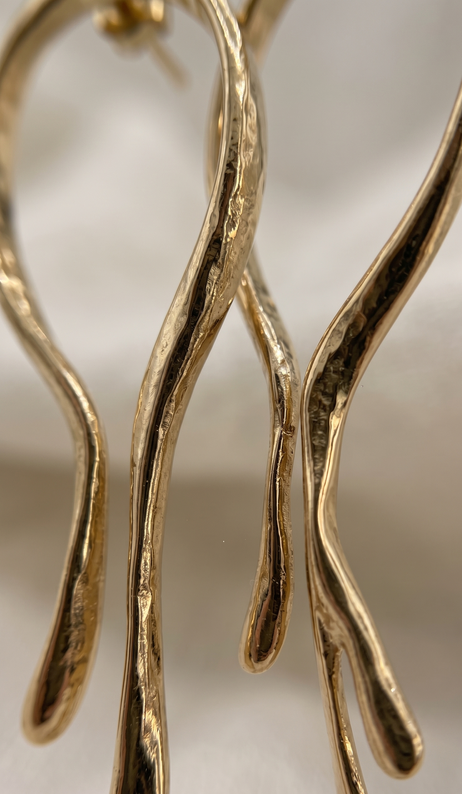 Gold branch-like earrings on a neutral background