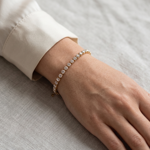 Hand wearing a diamond bracelet on a neutral background
