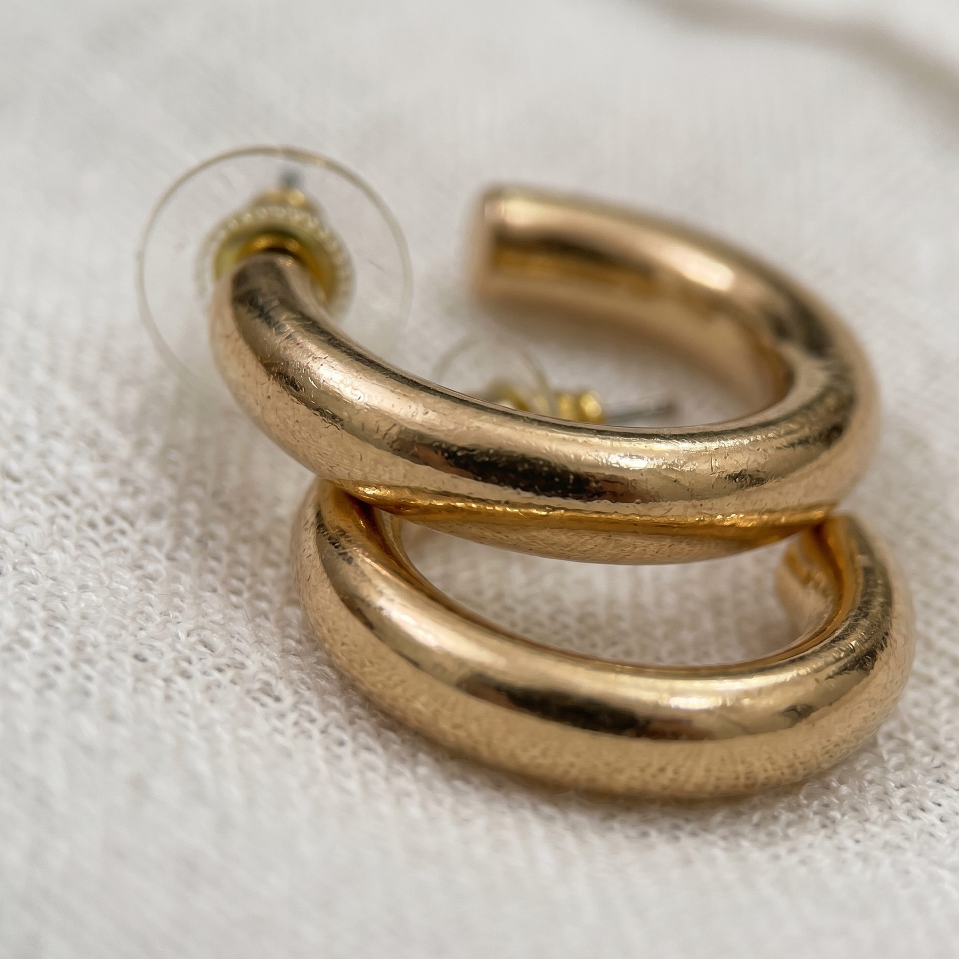 Gold hoop earrings on a light fabric background