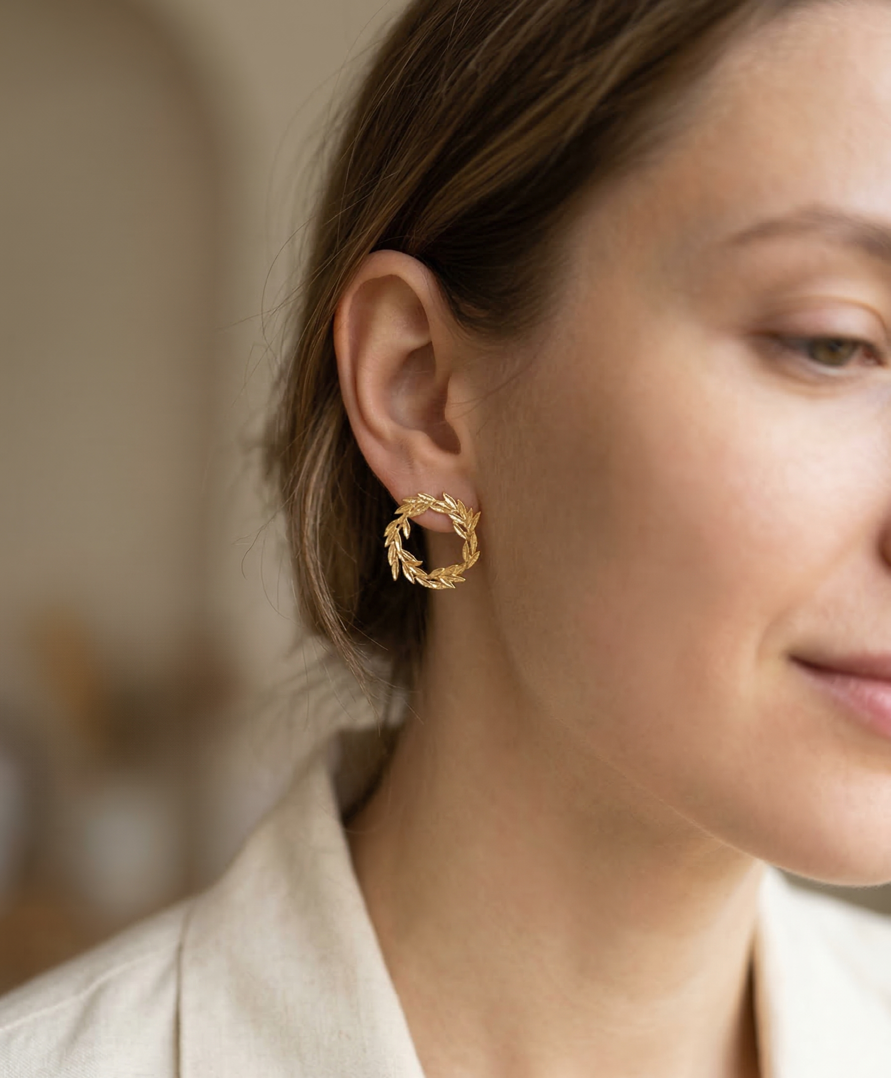 Close-up of a woman wearing gold hoop earrings with a blurred background