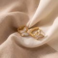 Gold butterfly earrings on beige fabric