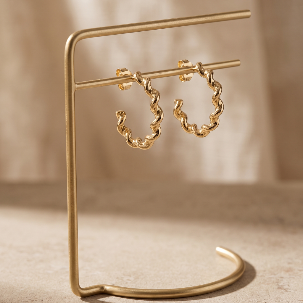 Gold chain hoop earrings on a matching gold stand against a beige background