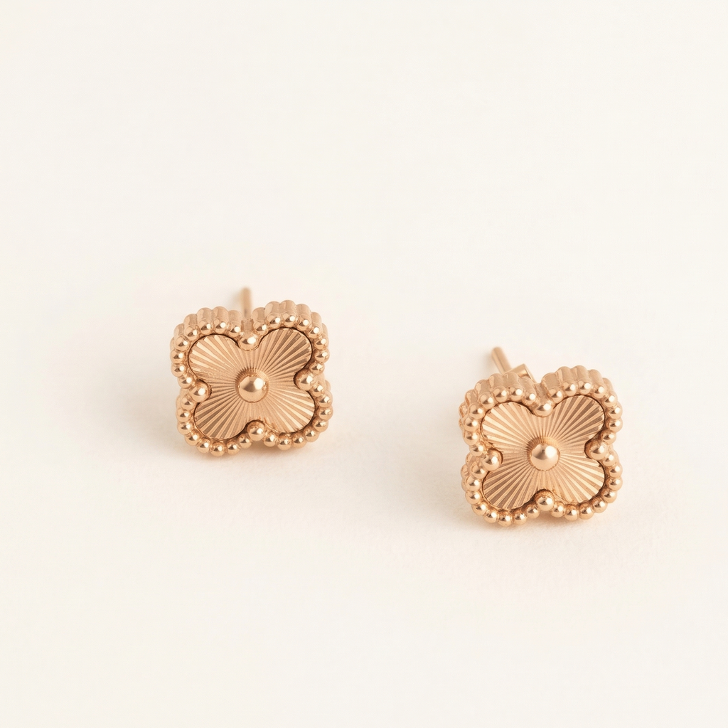 Pair of rose gold floral earrings on a light beige background
