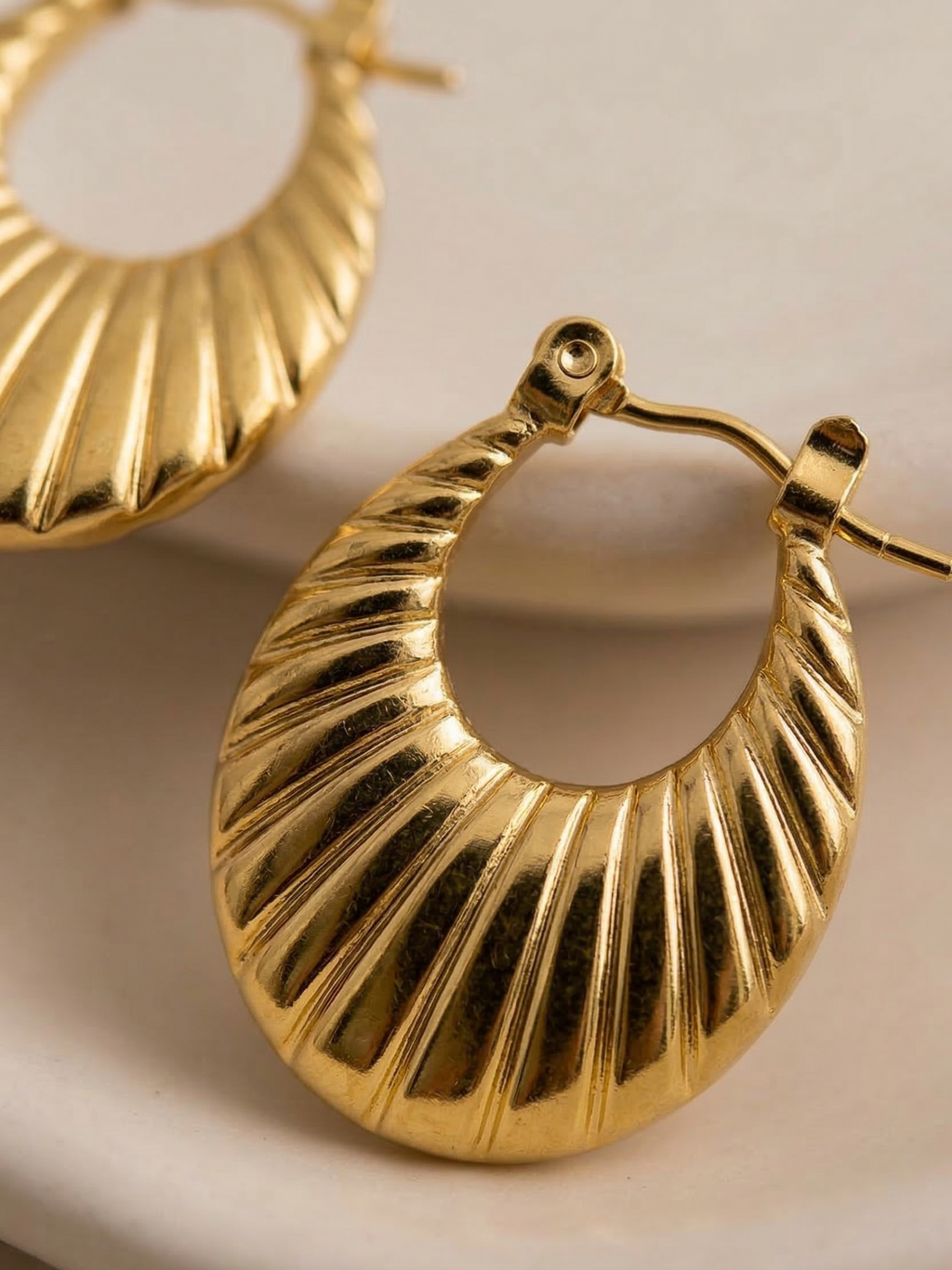 Gold hoop earrings on a beige background