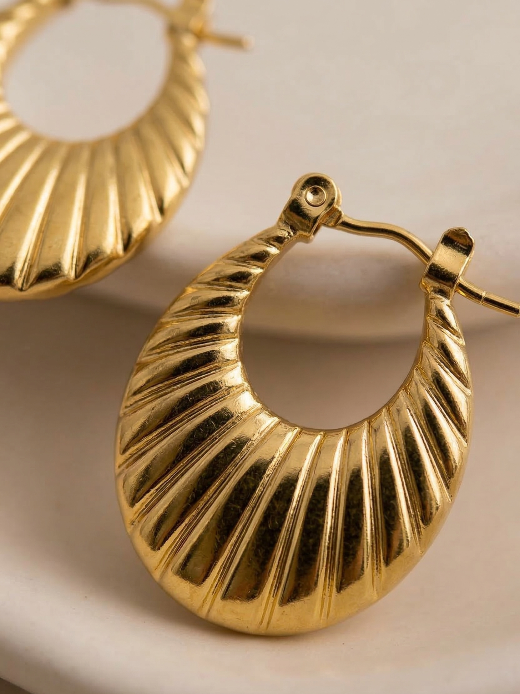 Gold hoop earrings on a beige background