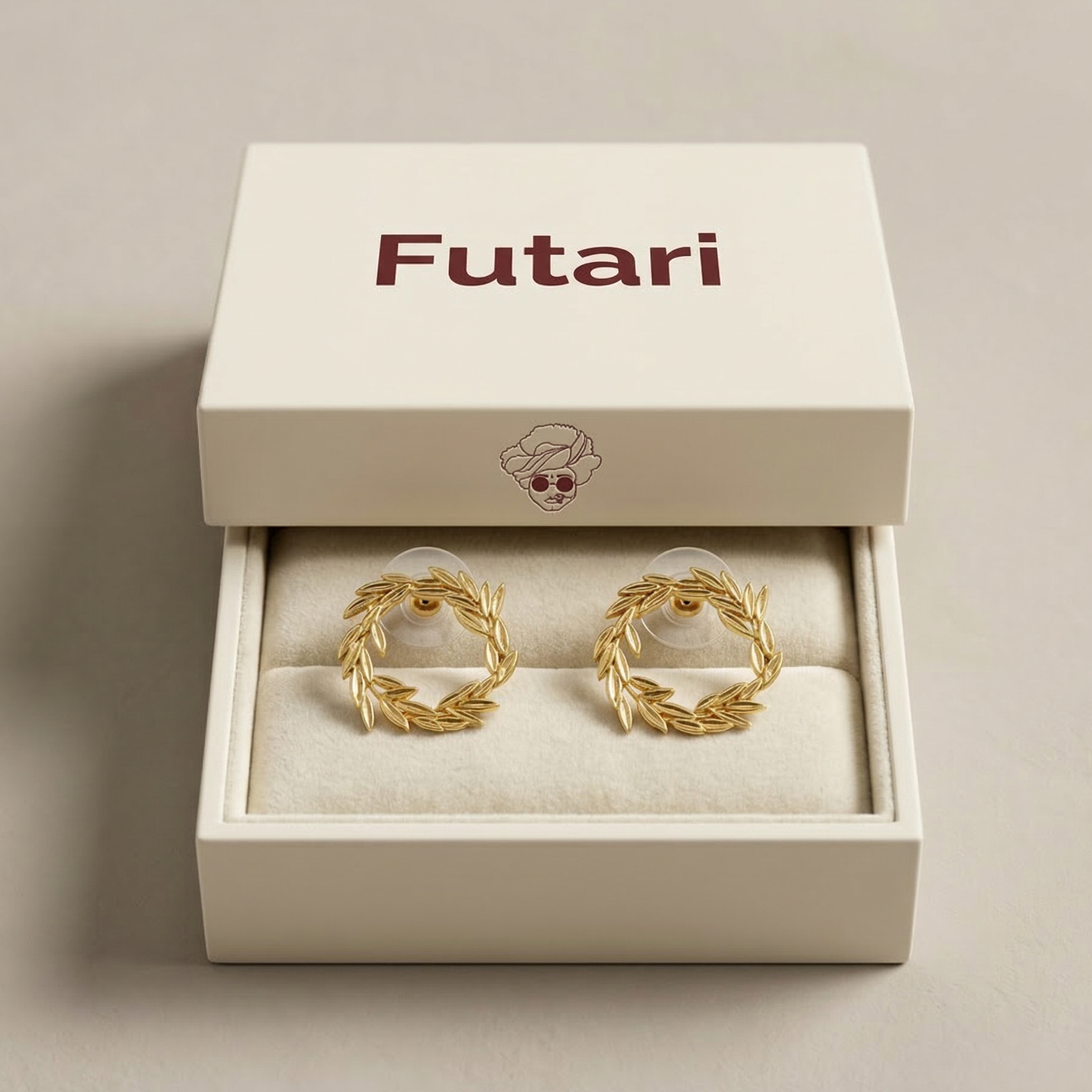 Gold earrings in a 'Futari' branded box on a beige background