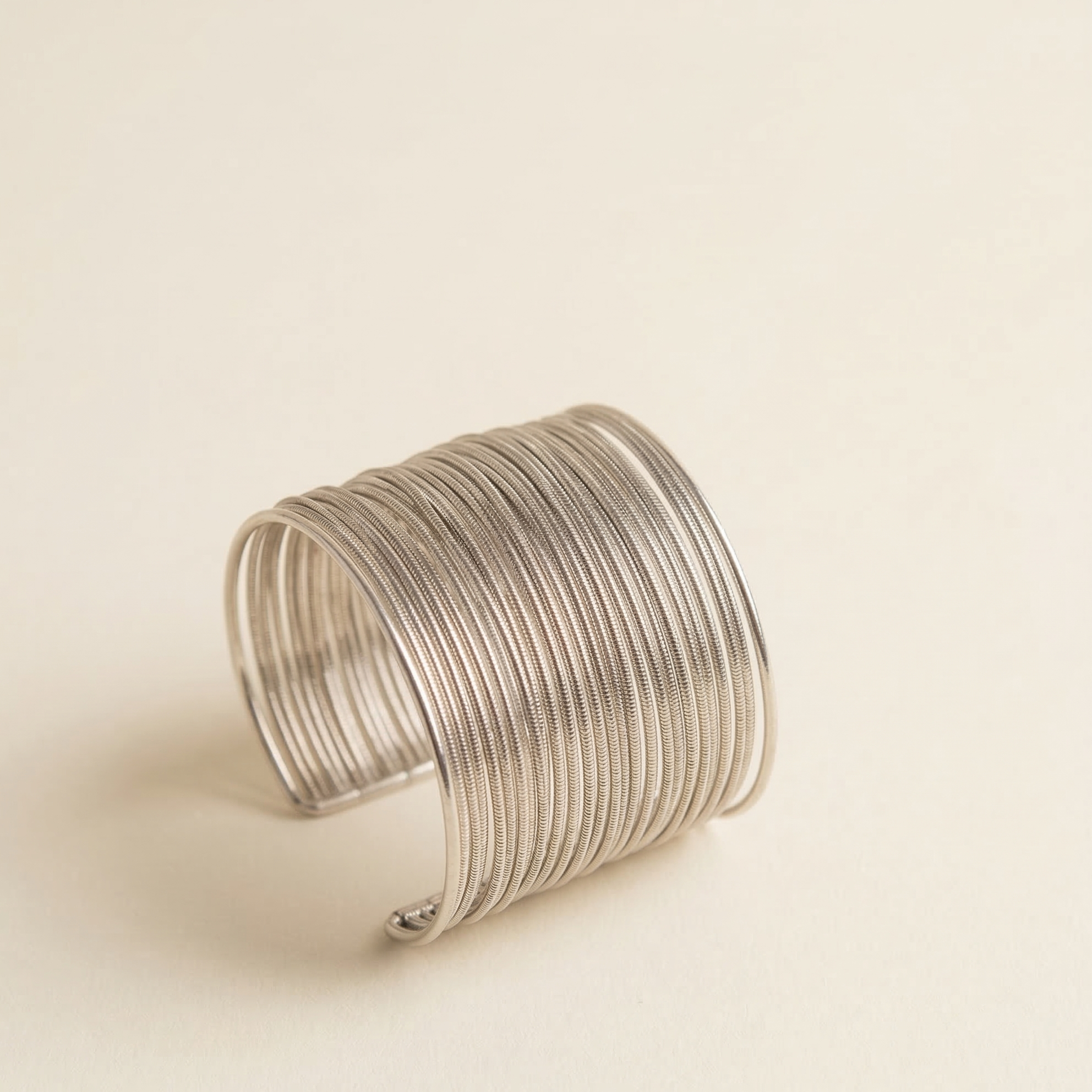 Silver wire cuff bracelet on a beige background