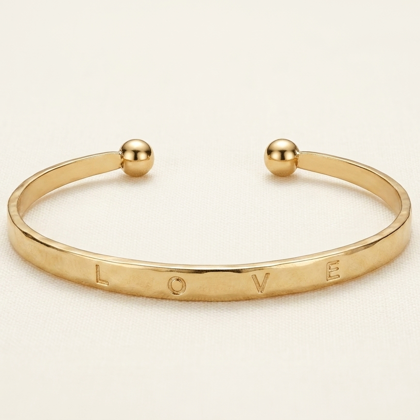 Gold bracelet with 'LOVE' engraving on a beige background