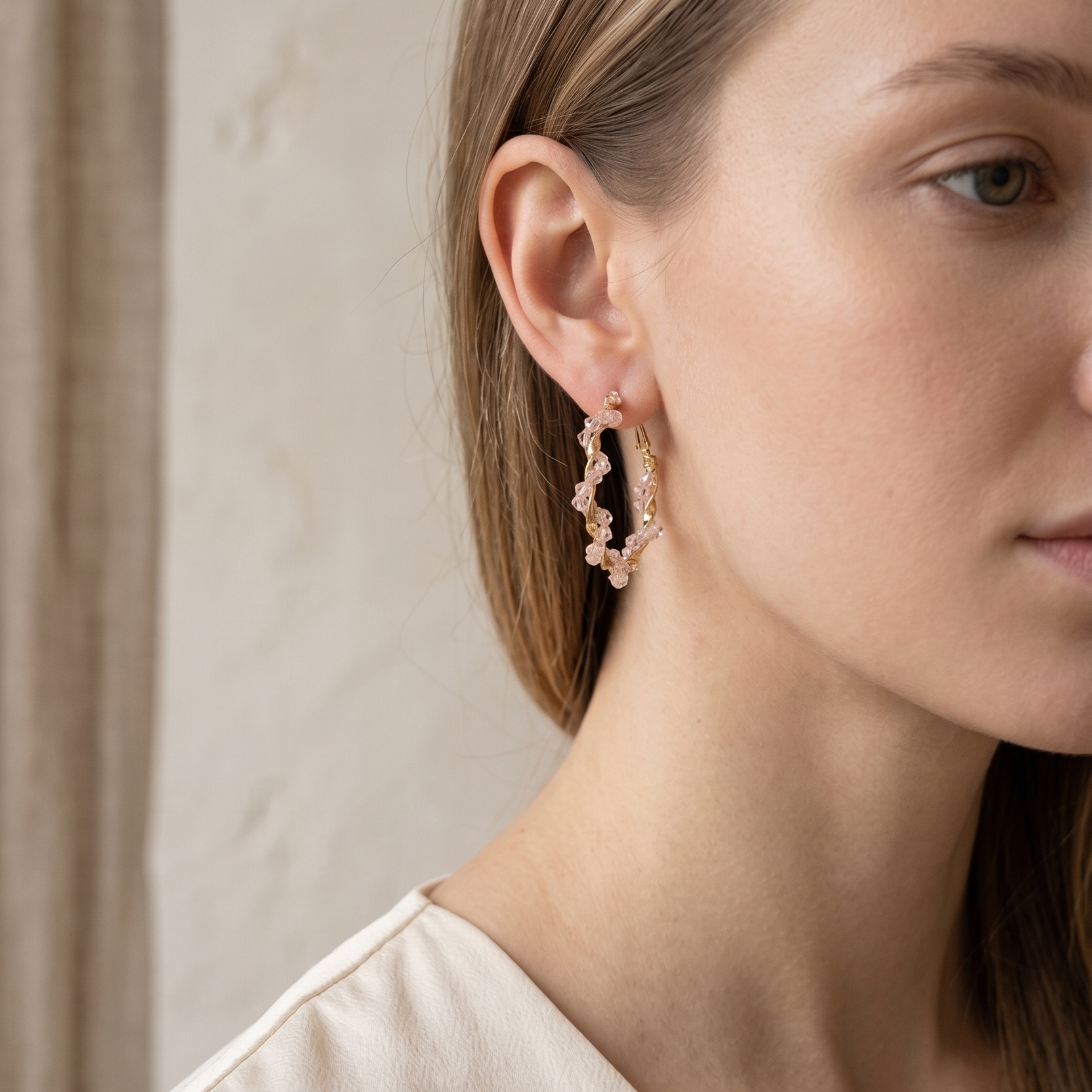 Close-up of a woman wearing floral hoop earrings with a neutral background