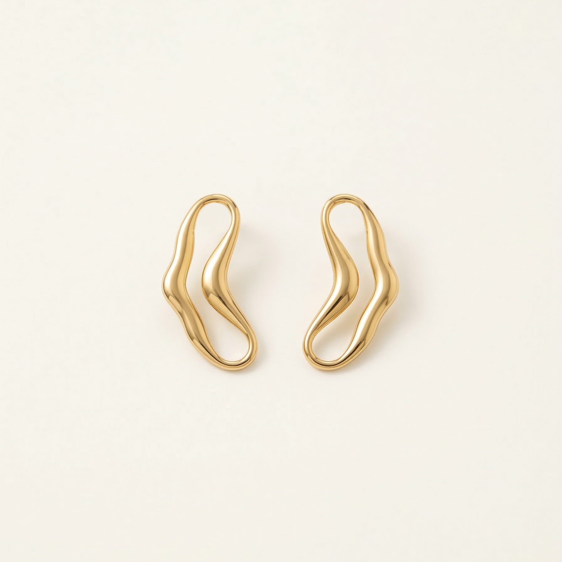 Pair of gold earrings on a light beige background