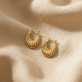 Gold hoop earrings on a beige fabric background