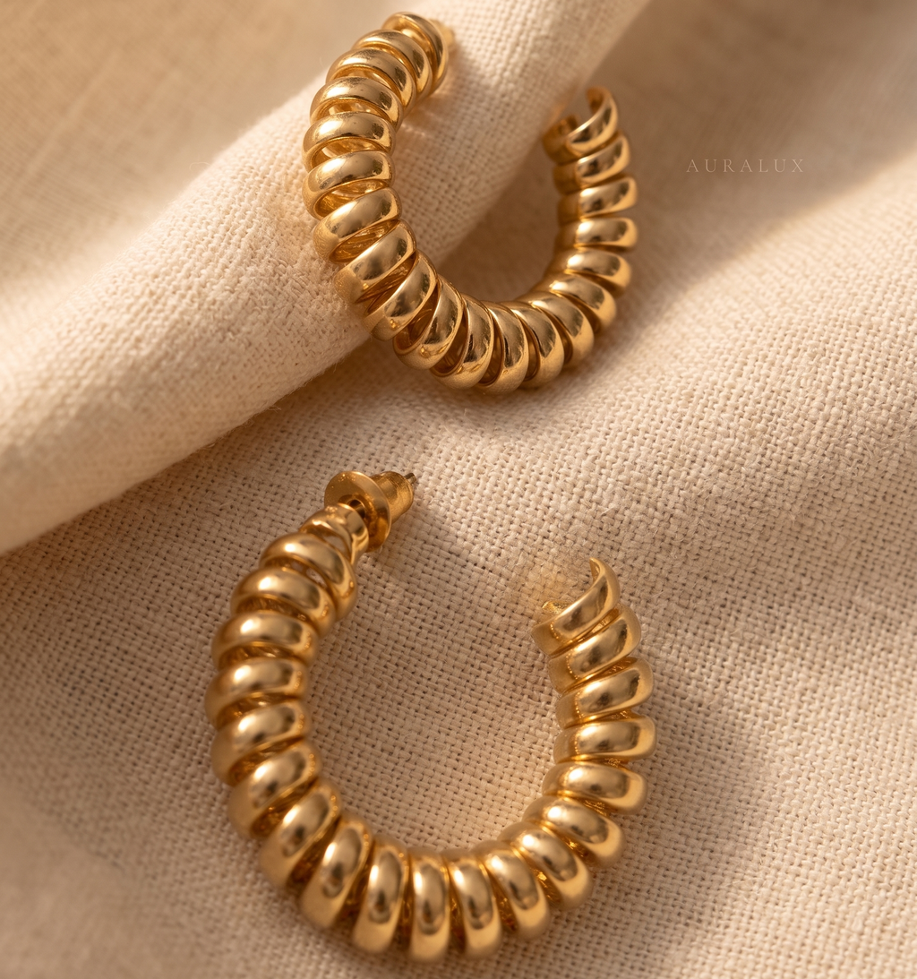 Gold hoop earrings on a beige fabric background
