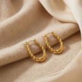 Gold hoop earrings on a beige fabric background