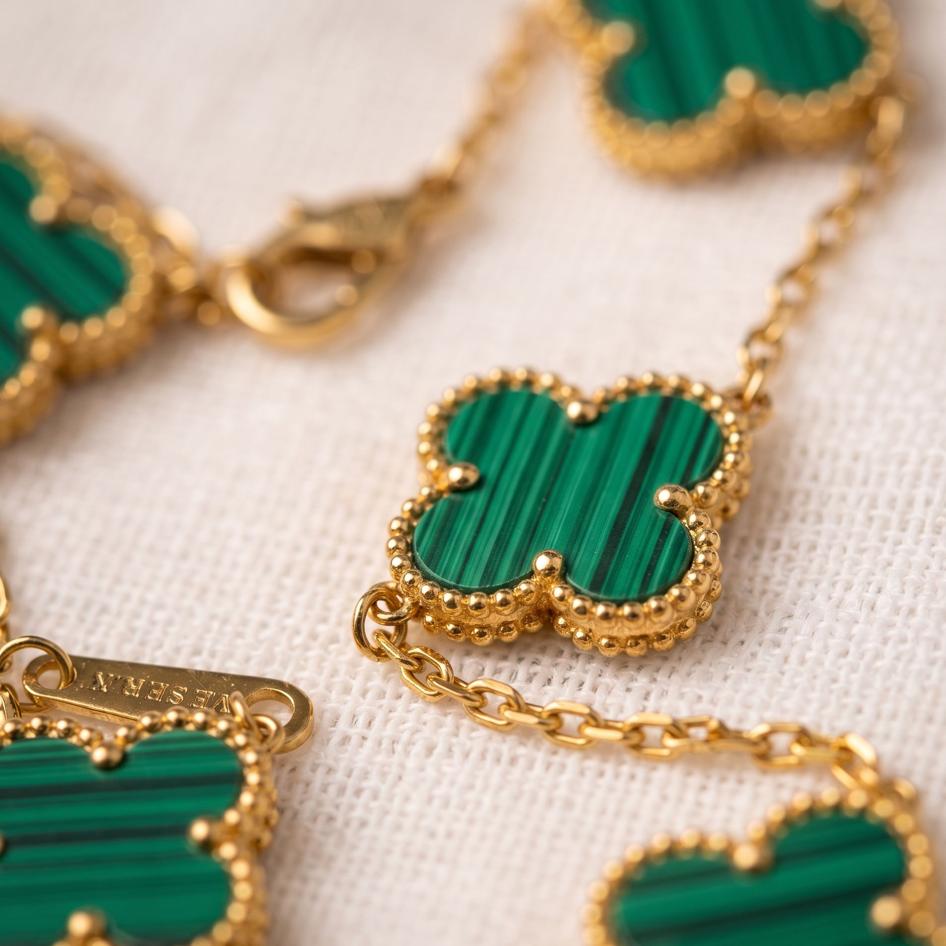 Gold necklace with green heart-shaped pendants on a white background