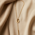 Gold necklace with a unique pendant on beige fabric
