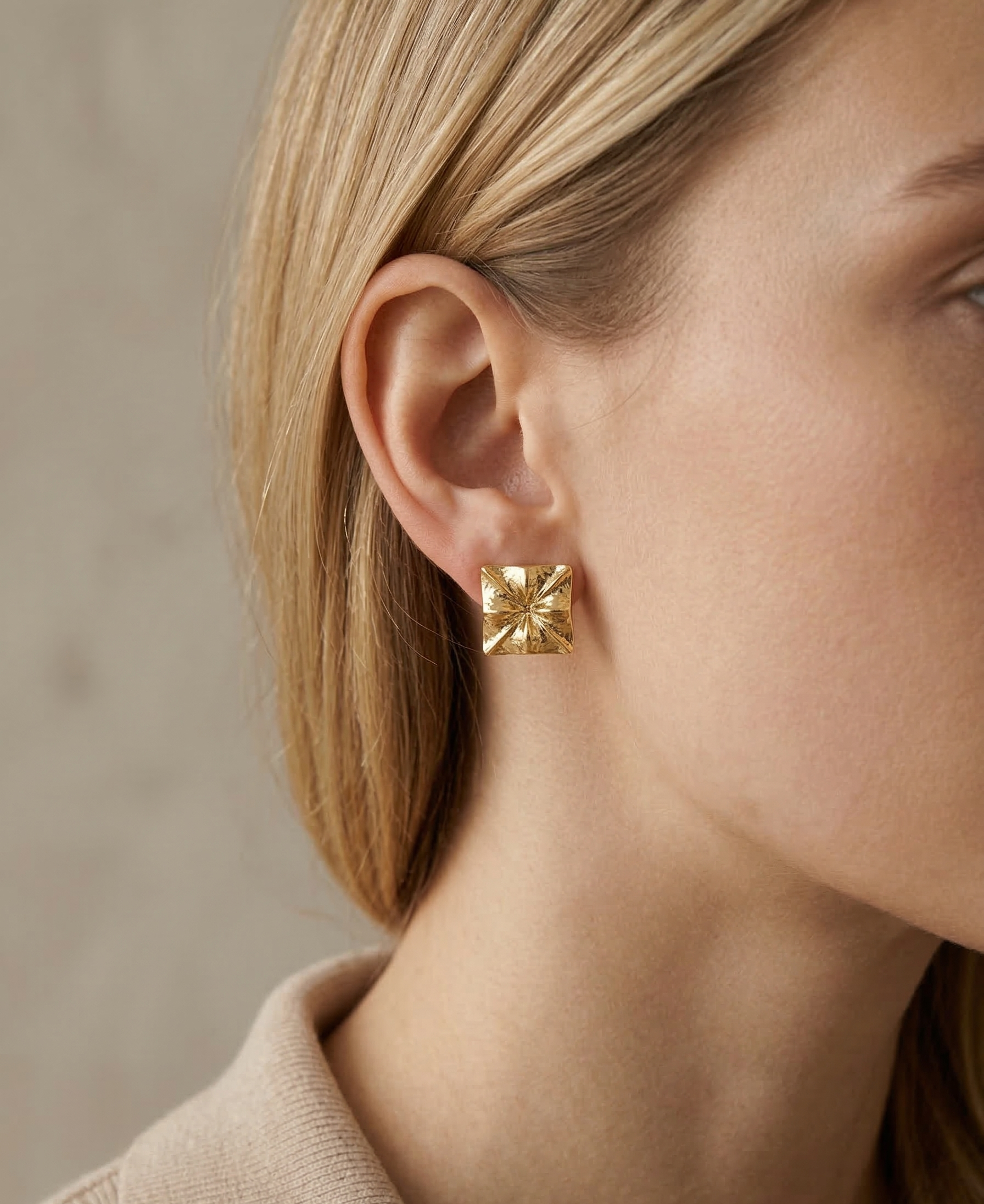 Gold earring worn by a person with a neutral background