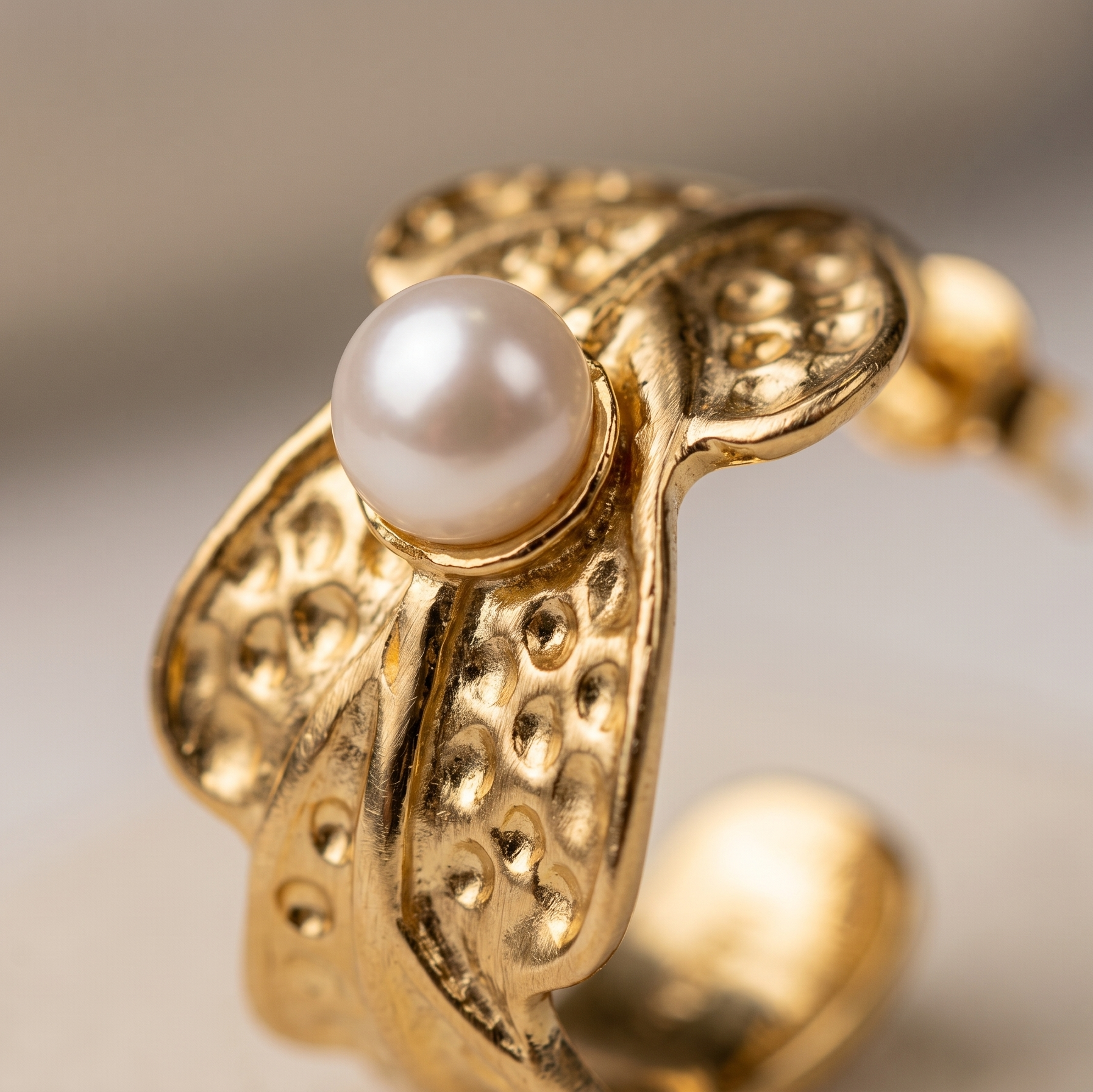 Gold earring with a pearl on a neutral background