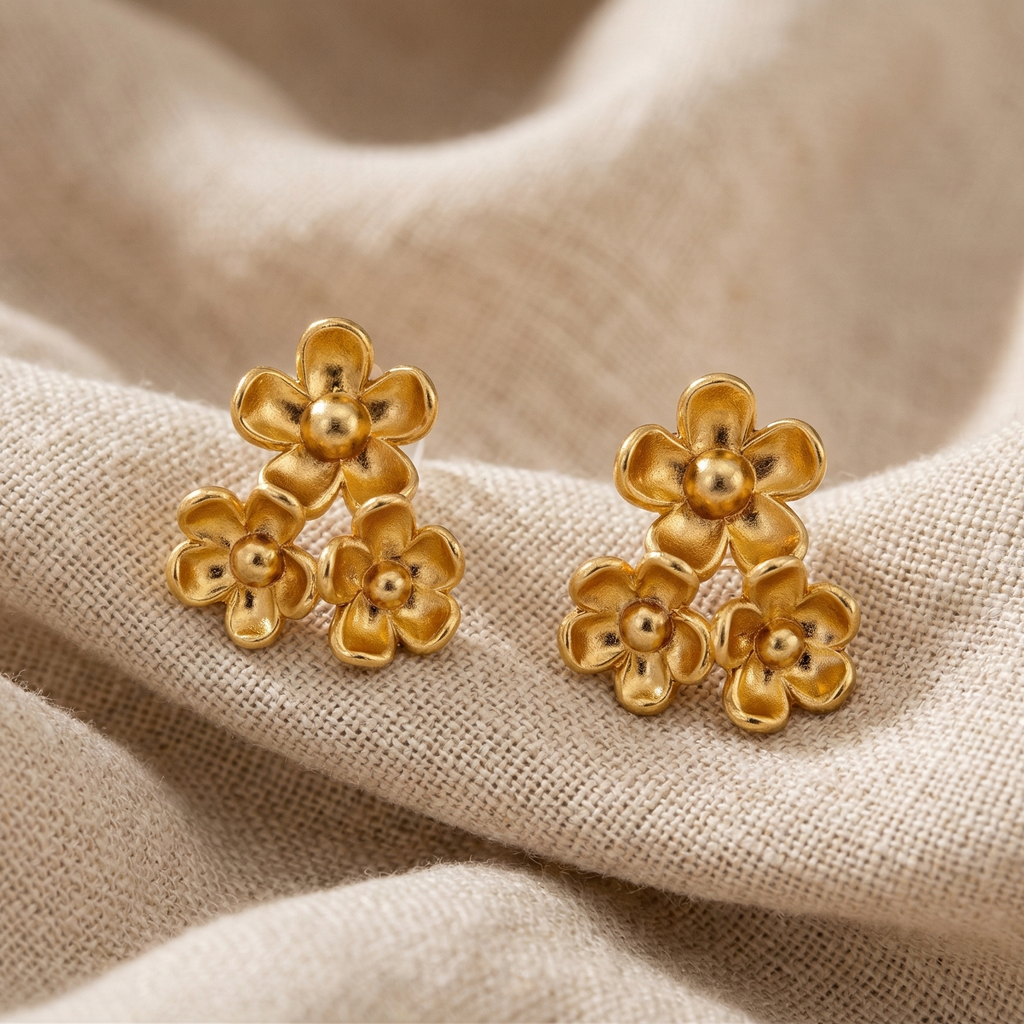 Gold flower-shaped earrings on beige fabric