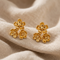 Gold flower-shaped earrings on beige fabric
